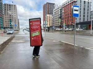 Промоутер с рекламой рюкзаком лайтбоксом за спиной